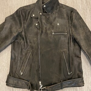 May include: A dark brown leather motorcycle jacket with a zipper closure, a belt, and multiple pockets.
