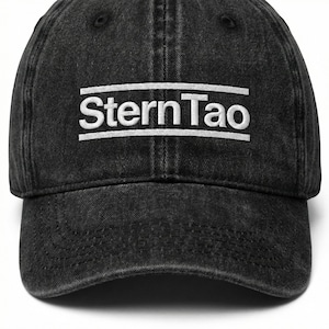 Könnte beinhalten: Schwarze Baseballkappe aus Denim mit dem weißen Text "SternTao", der auf der Vorderseite gestickt ist. Die Kappe hat einen gebogenen Schirm und ein sechsteiliges Design. Hergestellt aus strapazierfähigem, gewaschenem Denim-Material.