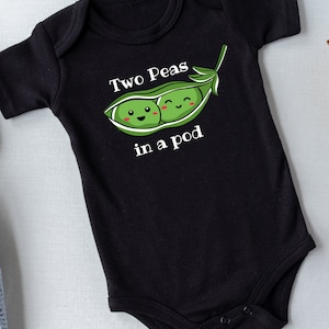 May include: Black baby onesie with a white graphic of two peas in a pod. The peas have smiling faces and are green. The text "Two Peas in a Pod" is written in white.