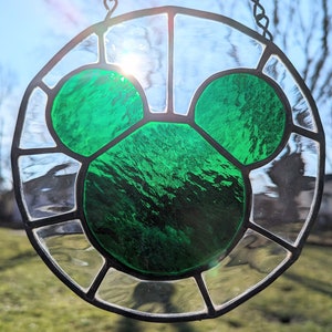 Może przedstawiać: Witrażowe okno wiszące na łańcuchu, przedstawiające zieloną sylwetkę Myszki Miki.