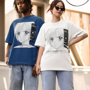 May include: Two people wearing blue and white t-shirts with a black and white anime character graphic and the text "PANCHIKO" on the front. The text is rotated vertically on the shirts. The people are wearing blue jeans.