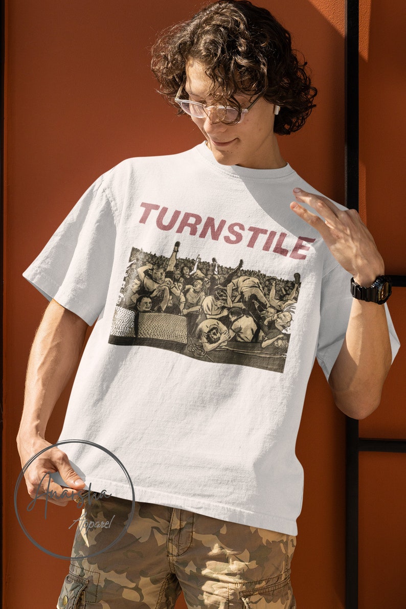 Puede incluir: Camiseta blanca con una imagen en blanco y negro de una multitud de personas con la palabra "TURNSTILE" impresa en rojo en la parte delantera.