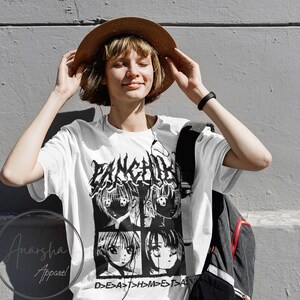 以下が含まれることがあります： 白地に黒と白のアニメ風の顔のグラフィックプリントが施されたTシャツ。顔の上に「FANCHI」という文字が、顔の下に「D>E>A>T>H>M>E>T>A」という文字がプリントされています。
