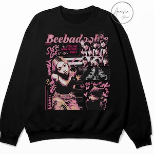 May include: Black sweatshirt with a pink and white graphic design. The design includes the text "Beebadook" and "Tell me how do you feel?" along with images of a woman and other graphics.