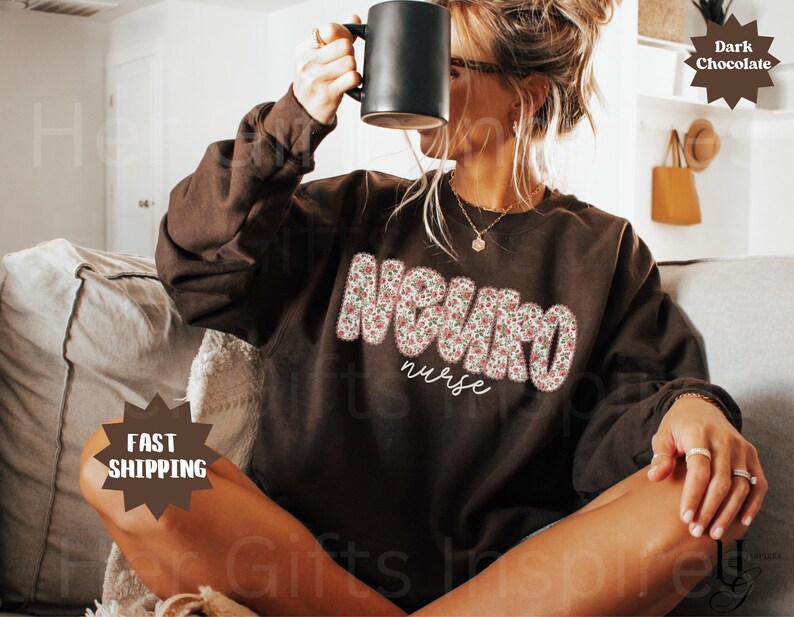 Puede incluir: Una sudadera de color chocolate oscuro con la palabra "NEURO" en letras grandes con estampado floral y la palabra "nurse" en una fuente cursiva m&aacute;s peque&ntilde;a. La sudadera es de manga larga y cuello redondo.
