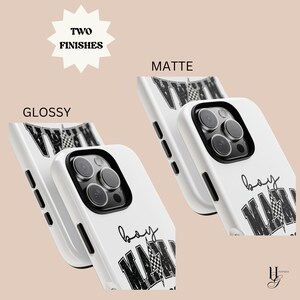 Puede incluir: Dos fundas blancas para iPhone con un dise&ntilde;o de bandera a cuadros en blanco y negro y el texto "boy mama" en negro. Las fundas se muestran en acabados brillante y mate.