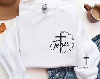 Può includere: Felpa bianca a maniche lunghe con una croce nera e il testo "THE WAY. THE TRUTH. THE LIFE Jesus" sul davanti. La manica destra ha una croce nera più piccola con il testo "JOHN 14.6".