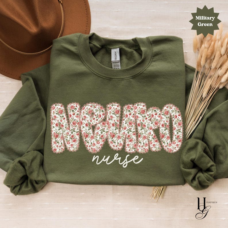 Puede incluir: Una sudadera verde oliva con la frase "NEURO nurse" en un dise&ntilde;o floral. La sudadera tiene cuello redondo y mangas largas. El texto "Military Green" est&aacute; en forma de estrella en la esquina superior derecha.