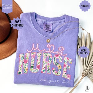 May include: A purple t-shirt with the text "Miss Nurse" in pink and white with floral accents. The text "Abigail, RN" is printed below the main text.
