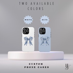 May include: Two phone cases with a blue bow design. The cases are available in white and blue. The text "TWO AVAILABLE COLORS" is at the top of the image. The text "WHITE" and "BLUE" are in stars below the text. The text "CUSTOM PHONE CASES" is at the bottom of the image.