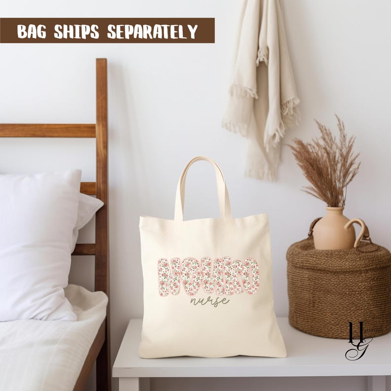 Puede incluir: Bolso tote de color crema con la palabra "NURSE" en un estampado floral. La palabra "nurse" est&aacute; escrita en cursiva debajo. El bolso tiene dos asas y est&aacute; sobre una mesa blanca. El texto "BAG SHIPS SEPARATELY" est&aacute; arriba.