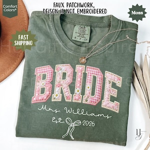 May include: A moss green t-shirt with the word "BRIDE" in pink patchwork letters, decorated with floral and gingham patterns. The text "Mrs. Williams Est. 2026" is below the word "BRIDE". The shirt also has the text "FAUX PATCHWORK, DESIGN IS NOT EMBROIDERED".