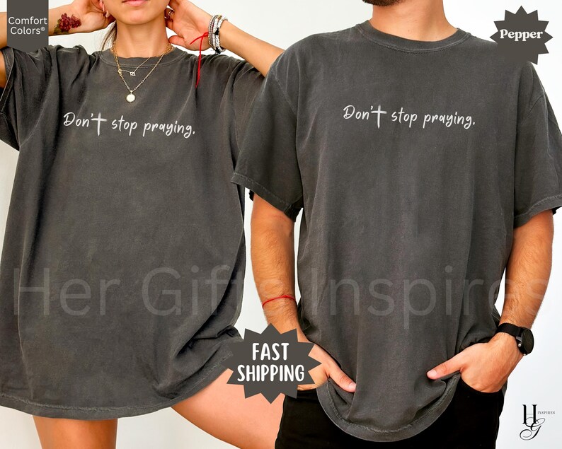 May include: Two dark gray t-shirts with the text "Don't stop praying" in white script. The shirts are a relaxed fit and have short sleeves. The image includes the words "Comfort Colors" and "Fast Shipping".