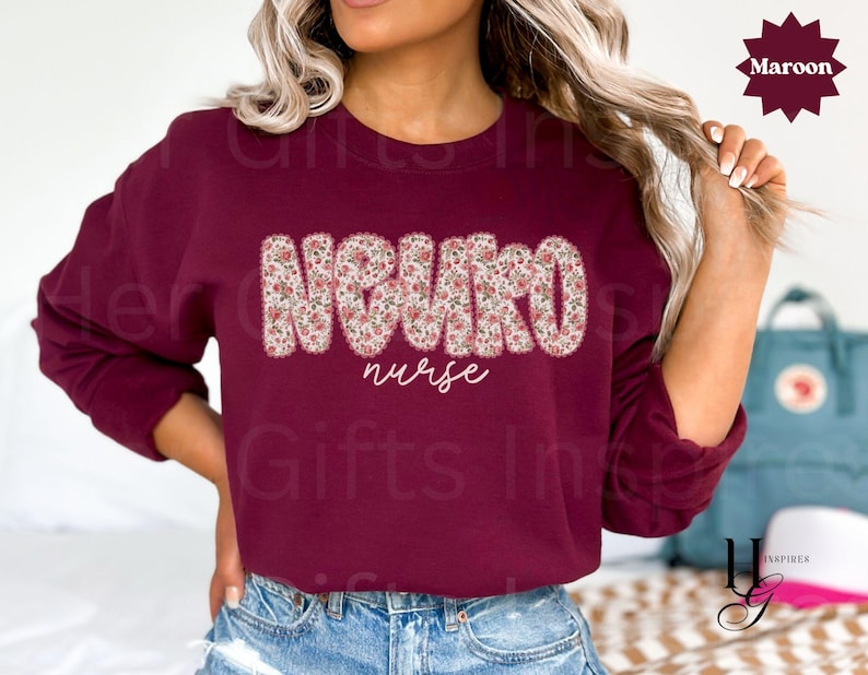 Puede incluir: Una sudadera burdeos con la palabra "NEURO" en un estampado floral en el pecho, con "nurse" escrito debajo en cursiva. La sudadera es de color burdeos liso.