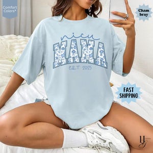 May include: Light blue Comfort Colors t-shirt with the text "nicu MAMA EST. 2025" in a floral design. The shirt has short sleeves and a relaxed fit. The word "nicu" is in a script font above the word "MAMA".