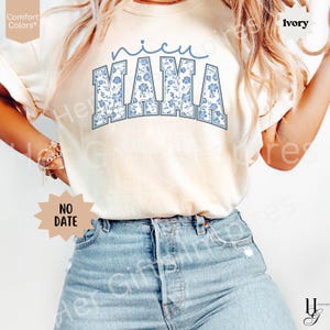 May include: Ivory-colored t-shirt with the text "nicu MAMA" in blue floral print. The shirt is a Comfort Colors brand. The text "NO DATE" is also visible on the shirt.