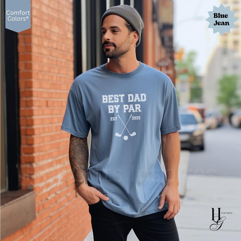 Peut inclure: T-shirt bleu jean Comfort Colors avec l'inscription blanche "BEST DAD BY PAR". Le motif comprend des clubs de golf crois&eacute;s, une balle de golf et l'ann&eacute;e "2025". Le t-shirt est de coupe d&eacute;contract&eacute;e.