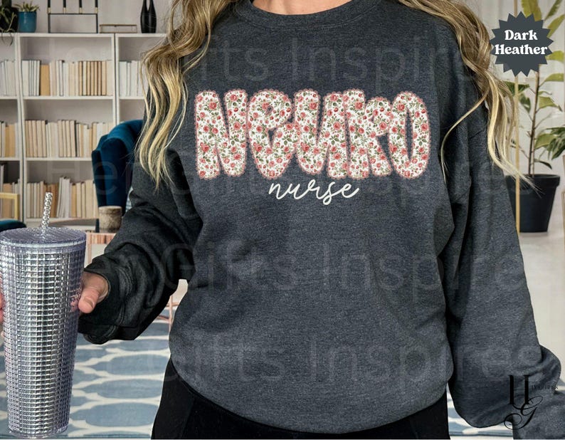 Puede incluir: Sudadera gris oscuro con la palabra "NURSE" en un dise&ntilde;o floral en el pecho. Debajo, la palabra "nurse" est&aacute; escrita en cursiva. Un vaso plateado con pajita se sostiene en la mano izquierda.