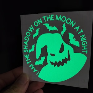 May include: A green glow-in-the-dark vinyl sticker with a silhouette of the character Jack Skellington from the movie The Nightmare Before Christmas. The sticker has the text "I am the shadow on the moon at night" around the silhouette.