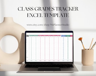 May include: A laptop computer displaying a spreadsheet with the title "Class Grades Tracker Excel Template" and the website address "www.etsy.com/shop/MsPlannerStudio". The laptop is on a white desk with a beige vase and paintbrushes.
