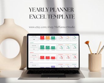 May include: A laptop computer displaying a yearly planner Excel template on the screen. The template includes a progress bar for each month, showing the percentage of tasks completed, in progress, and not started. The laptop is on a white desk with a beige vase and paintbrushes.
