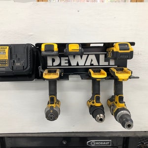 May include: A black metal wall-mounted storage rack with a DeWalt logo. The rack holds four yellow and black cordless drills and a DeWalt battery charger.