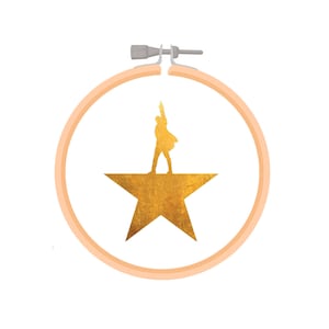 May include: A gold star with a silhouette of a person standing on top of it. The star is inside a peach-colored embroidery hoop.