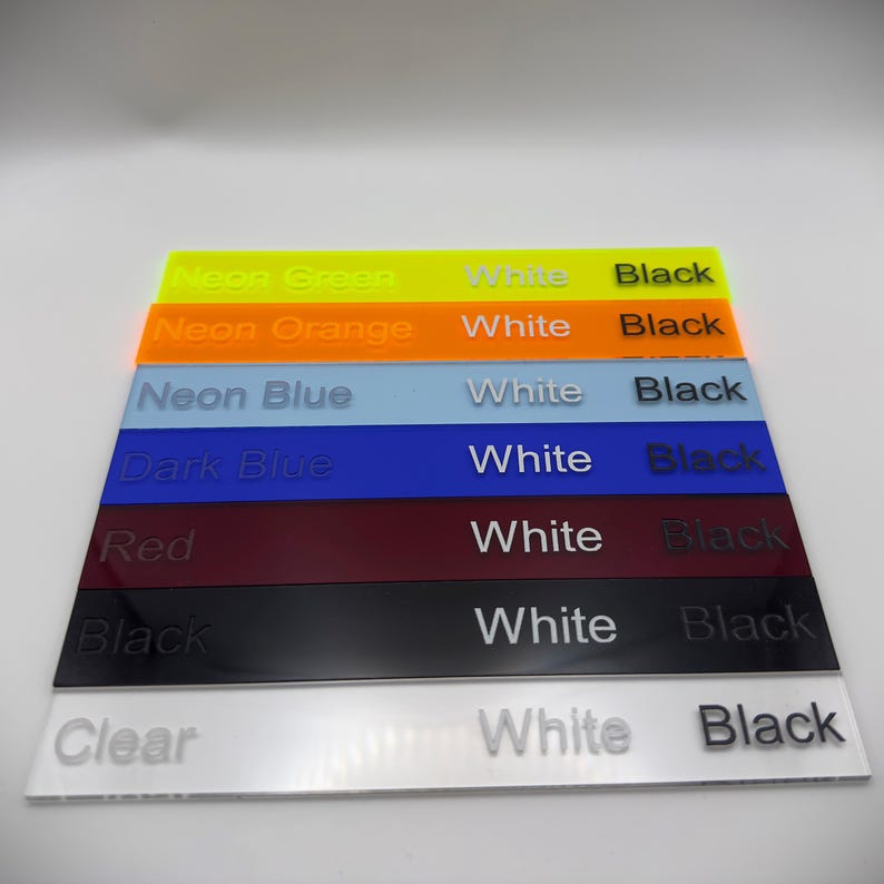 May include: A stack of acrylic color samples in neon green, neon orange, neon blue, dark blue, red, black, and clear. Each sample has the word "White" and "Black" printed on it.