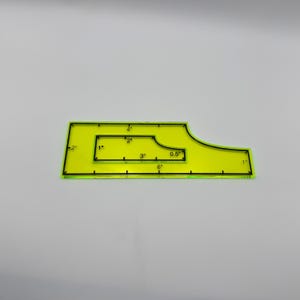 May include: A neon yellow quilting ruler with black markings. The ruler has various measurements in inches, including 1", 2", 3", 4", 6", and 0.5". The ruler is designed with a unique shape for quilting projects.