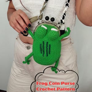 以下が含まれることがあります： 黒と白のチェーンストラップが付いた、緑色のカギ針編みのカエル小銭入れ。 カエル型の財布は、腕と脚を備えた詳細なデザインで、「Frog Coin Purse Crochet Pattern」というテキストが吹き出しの中にあります。