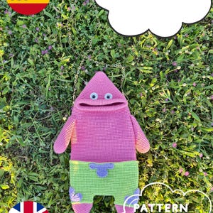 May include: A pink crocheted Patrick Star-shaped bag with a green shorts design. The bag has a chain strap and is set against a backdrop of green grass and flowers. Text in the image reads "PATTERN ENGLISH" and "PATRÓN DE AMIGURUMI EN ESPAÑOL".