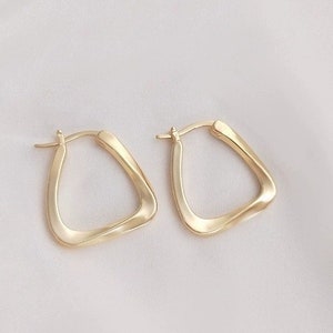 May include: A pair of gold-toned hoop earrings with a twisted, geometric design.