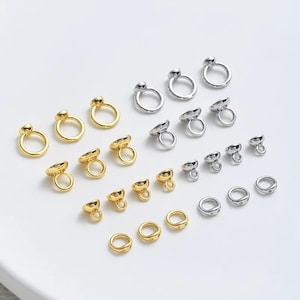 May include: A collection of gold and silver metal jewelry findings, including jump rings, bead caps, and end caps. These findings are perfect for making jewelry, such as necklaces, bracelets, and earrings.