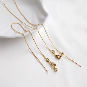 May include: Three gold chain extenders of varying lengths. The extenders are made of a delicate, fine chain and have a small ball at the end.