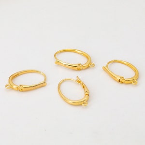 May include: Four gold-toned earring hooks with a hinged closure. The hooks are oval shaped and have a smooth finish.
