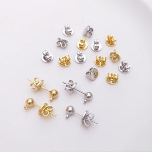 Peut inclure: Un ensemble de dos d'oreille en or et en argent. Les dos sont ronds et ont une petite boucle à l'arrière. Il y a aussi deux paires de tiges d'oreille avec des extrémités en boule, une paire en or et une paire en argent.