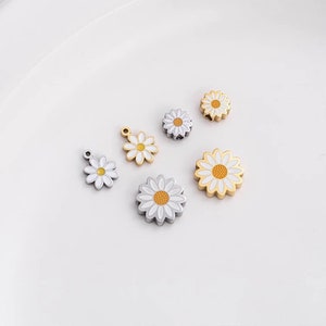 May include: Assortment of small, white daisy charms with yellow centers. Some charms are gold-toned and others are silver-toned. The charms are perfect for jewelry making or adding a touch of whimsy to crafts.