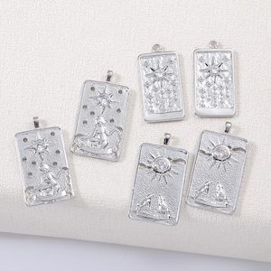 May include: Silver-toned rectangular pendants with various celestial and figurative designs. Each pendant features a bail for attaching to a chain. The designs include stars, suns, and figures, with a textured background.