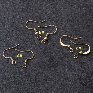 May include: Three gold-toned earring hooks with a small ball at the end. The hooks are labeled A#, B#, and C#.