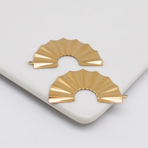May include: Two gold metal fan-shaped earring charms with a hole at the top for attaching to jewelry.