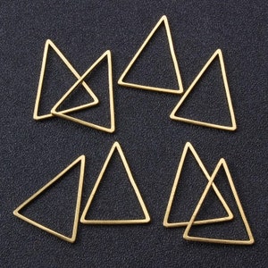 May include: A set of eight gold-toned triangle-shaped metal charms. The charms are all the same size and shape, and they have a smooth, polished finish.