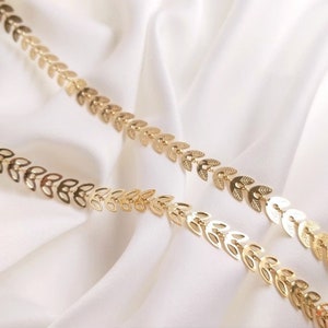 Puede incluir: Collar de cadena de oro con un diseño de hojas. La cadena está hecha de pequeñas hojas interconectadas.