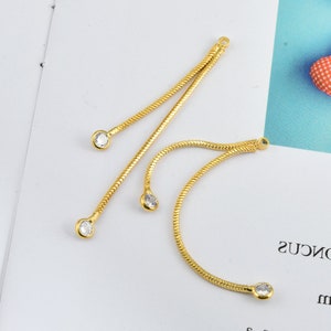 May include: Four gold chain connectors with clear rhinestone accents. The chains are snake chain style and have a loop at the top for attaching to jewellery.