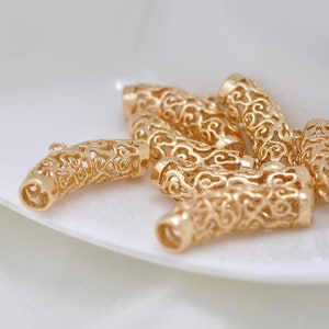 May include: Gold-toned metal end caps for jewelry making. The caps have a delicate, intricate design with a filigree pattern.