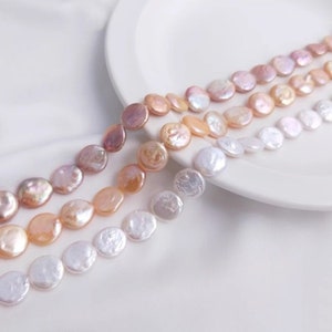 May include: A strand of round, flat, iridescent pearls in shades of white, pink, and peach. The pearls are arranged in a graduated pattern, with the largest pearls at the top and the smallest pearls at the bottom.