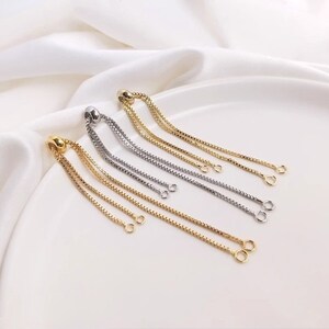 Op de afbeelding: Drie verstelbare kettingarmbandverlengers in goud en zilver met een schuifknop en twee springringen aan het einde van elke ketting.