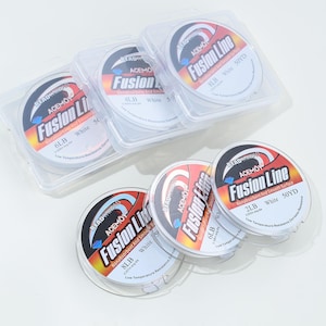 以下が含まれることがあります： 透明なプラスチックケースに入った白い釣り糸の複数のスプール。赤、白、青のラベルには「Fusion Line」の文字と、ポンドとヤードでの重量情報が記載されています。