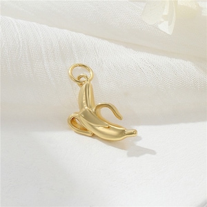 May include: A gold-colored banana charm pendant. The charm is shaped like a banana with a curved stem.