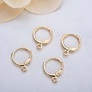May include: Four gold-toned hoop earring findings with a jump ring attached to the bottom of each hoop.