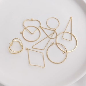 Puede incluir: Surtido de formas de colgantes de metal dorado, que incluyen un corazón, un círculo, un diamante y un triángulo. Los colgantes tienen un diseño texturizado y trenzado.